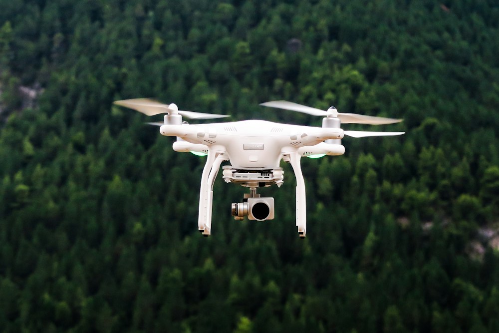 Dron blanco volando sobre un bosque