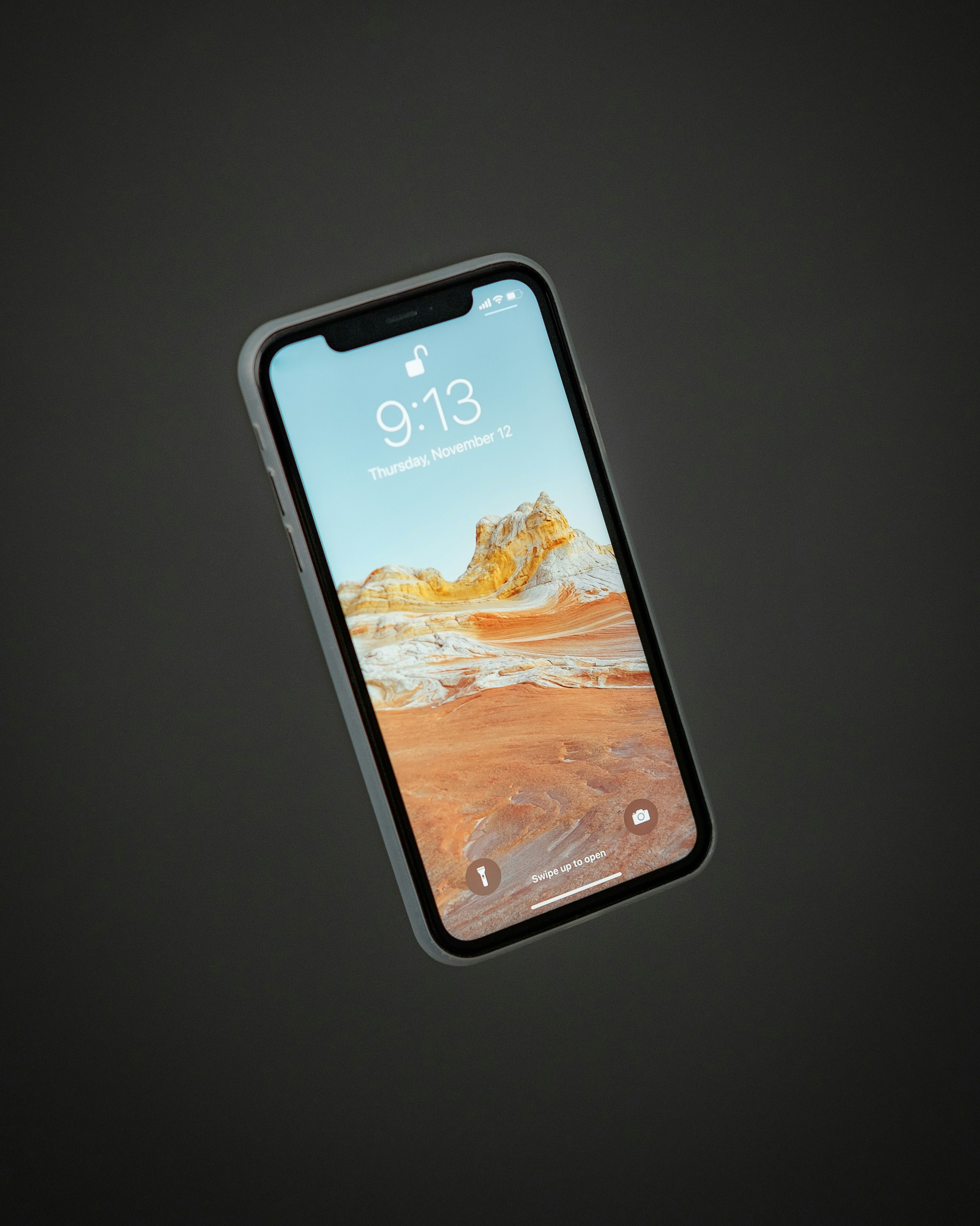 Celular encendido con un fondo de pantalla en tonos naranja y arena sobre fondo oscuro