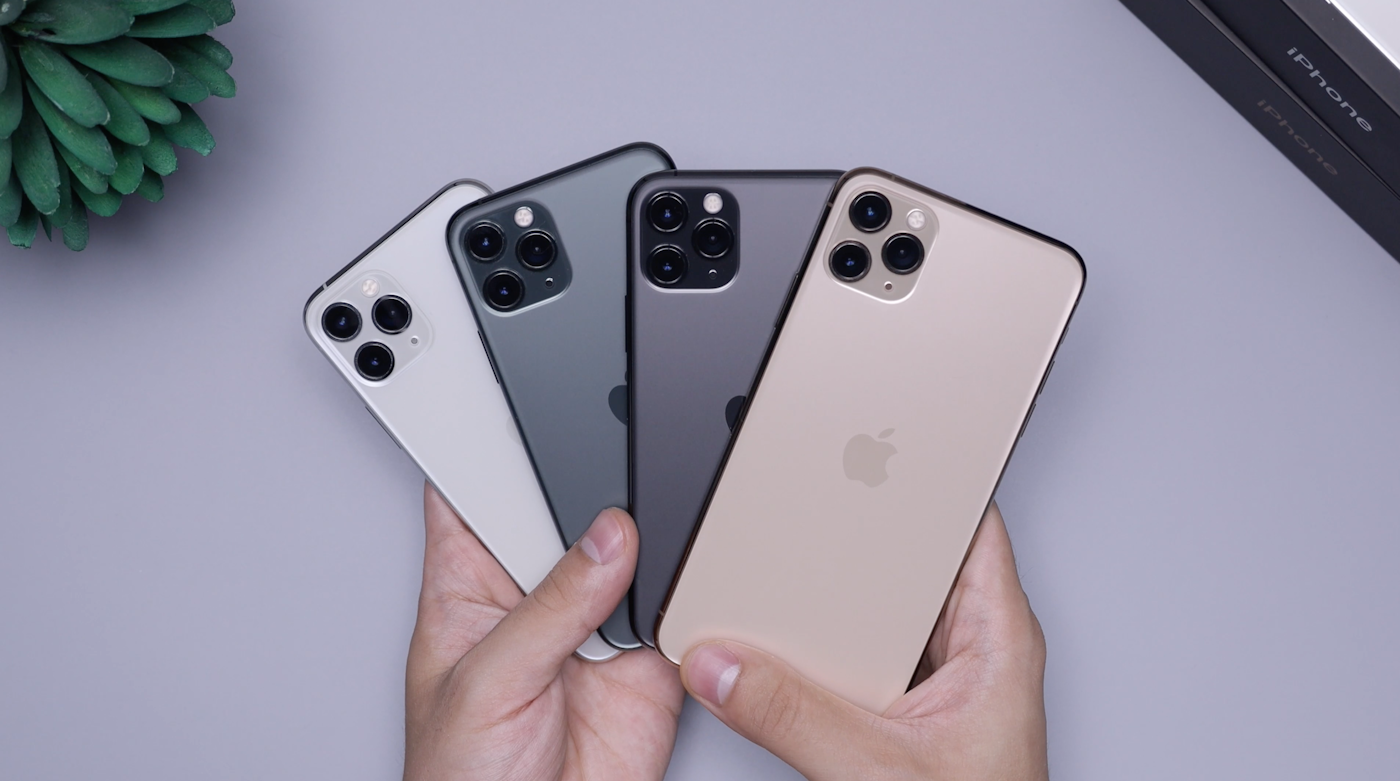 Manos sosteniendo cuatro celulares de distintos colores
